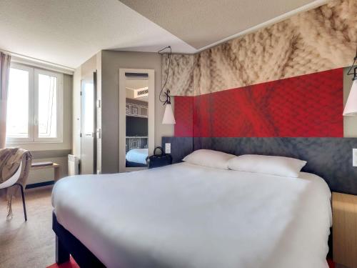 a bedroom with a large white bed and a red wall at ibis Rueil-Malmaison Centre in Rueil-Malmaison