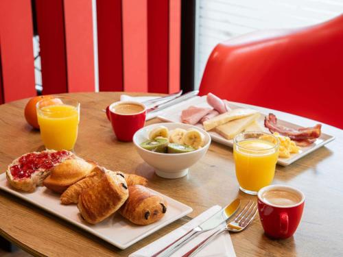 a table with a breakfast of pastries and orange juice at ibis Versailles Château in Versailles