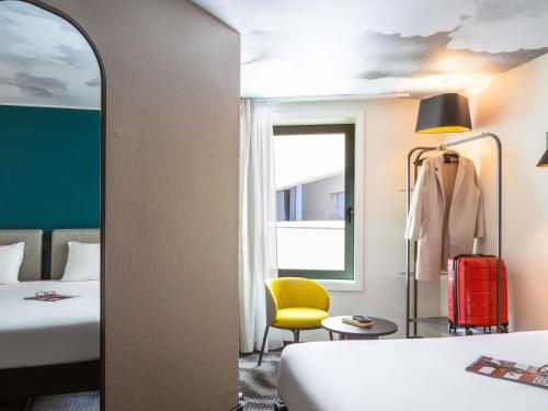 a hotel room with two beds and a yellow chair at ibis Paris Coeur d'Orly Airport in Orly