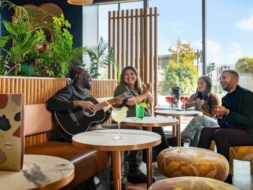 a group of people sitting in a restaurant playing guitar at ibis Paris Coeur d'Orly Airport in Orly