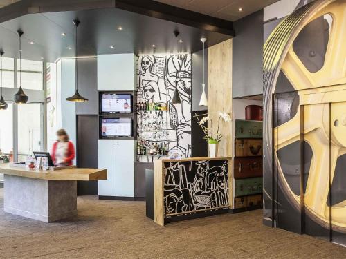 a lobby with a counter and a person in the background at ibis Poitiers Centre in Poitiers