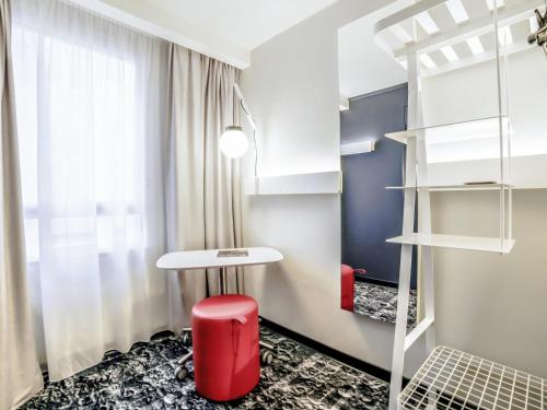 une petite pièce avec un tabouret rouge et une table dans l'établissement ibis La Rochelle Centre Historique, à La Rochelle