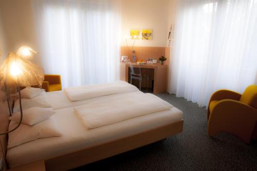 a bedroom with a white bed with a desk and curtains at Mintrops Stadt Hotel Margarethenhöhe in Essen