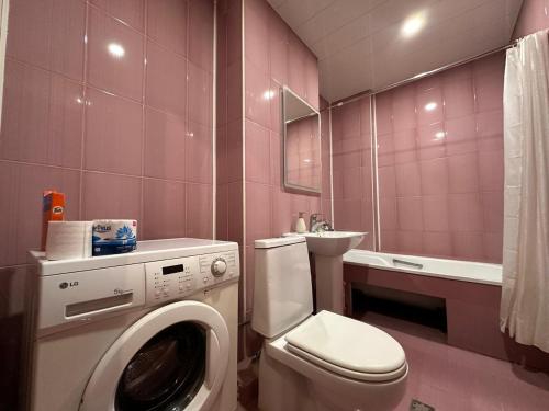 a pink bathroom with a washing machine and a sink at Republic square 2 bedroom 2 bathroom in Yerevan