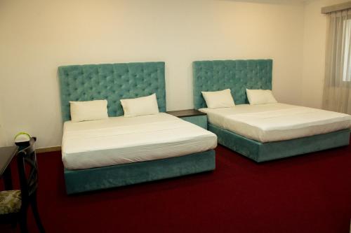 two beds in a room with blue headboards at Sorabora Gedara Hotel in Mahiyangana