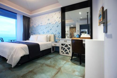 a bedroom with a bed and a desk and a window at Hualien S.E.A. B&B in Hualien City