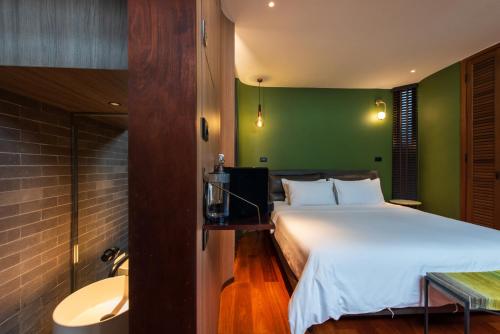 a bedroom with a white bed and a green wall at Na Tanao 1969 in Bangkok