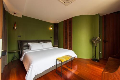a bedroom with a white bed and green walls at Na Tanao 1969 in Bangkok