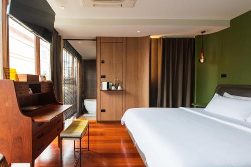 a bedroom with a bed and a desk and a bathroom at Na Tanao 1969 in Bangkok