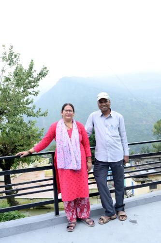 a man and a woman standing on top of a mountain at maa kalishila home stay in Ukhimath