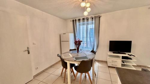 a room with a table and a television and a kitchen at Jolie T3 Dans le parc des Thermes in Allevard