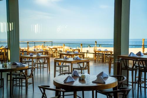 a restaurant with tables and chairs with the beach in the background at Sentido Naga Bay - Adults friendly in Hurghada