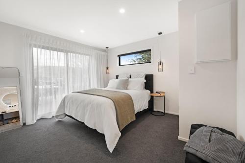 a white bedroom with a large bed and a window at Bellamy Station - Luxury on the Clutha Gold Trail in Evans Flat