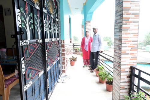 a man and a woman standing on a balcony at maa kalishila home stay in Ukhimath