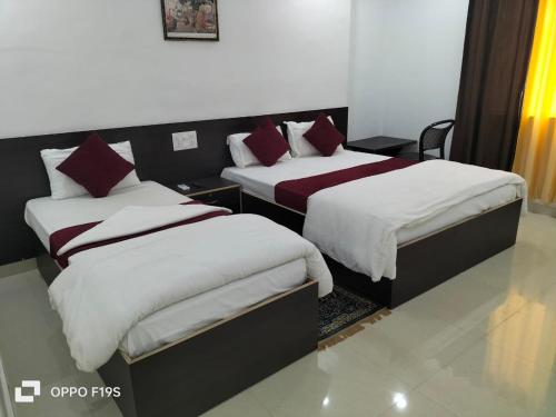 2 camas en una habitación con almohadas blancas y rojas en Hotel Temple View, en Bodh Gaya