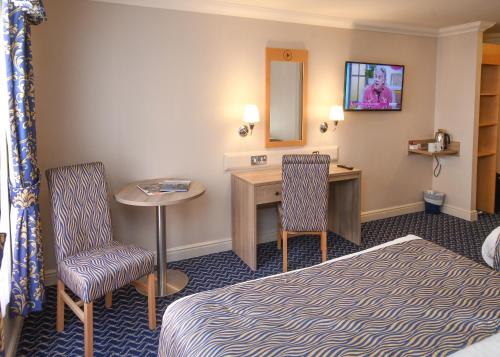 a hotel room with a bed and a desk and chairs at The Queens Hotel & Victoria Cloisters Apartments in York
