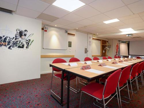 a conference room with a long table and red chairs at ibis Toulouse Centre in Toulouse
