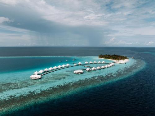 an island in the ocean with umbrellas in the water at Diamonds Athuruga Maldives Resort & Spa in Athuruga Island