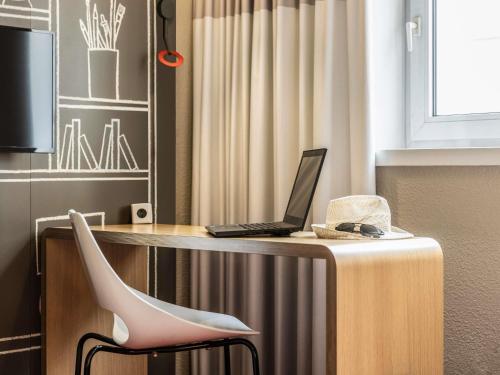 a laptop computer sitting on a table with a chair at ibis Toulouse Pont Jumeaux in Toulouse