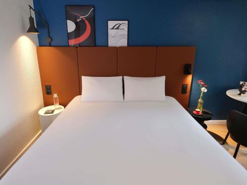 a bedroom with a large white bed with a blue wall at ibis Toulouse Pont Jumeaux in Toulouse