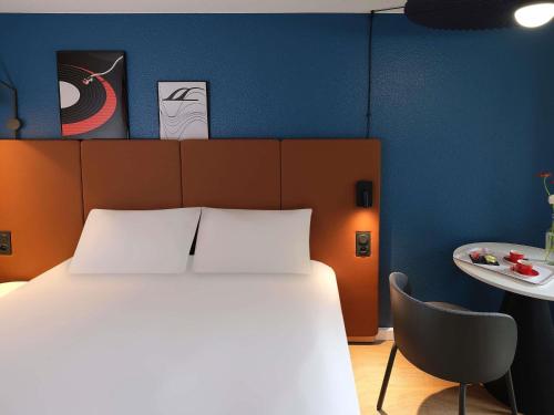 a bedroom with a white bed and a chair at ibis Toulouse Pont Jumeaux in Toulouse