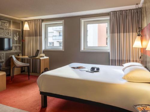 a hotel room with a large bed and a desk at ibis Toulouse Pont Jumeaux in Toulouse