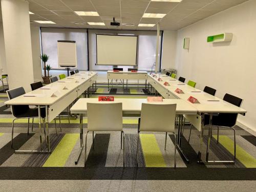 a conference room with tables and chairs and a screen at ibis Toulouse Pont Jumeaux in Toulouse