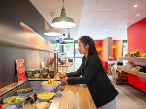 a woman preparing food in a restaurant kitchen at ibis Hotel München City in Munich