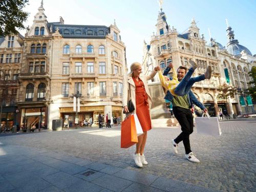 a man and woman walking down a street with shopping bags at ibis Antwerpen Centrum in Antwerp