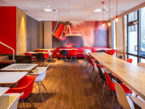 a restaurant with red chairs and a long table at Ibis Brussels City Centre in Brussels