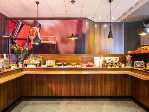 a restaurant with a counter with food on it at ibis Gent Centrum Opera in Ghent