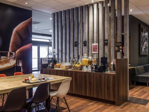 a bar in a restaurant with a table and chairs at ibis Gent Centrum Opera in Ghent