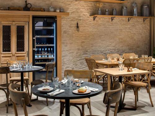 a restaurant with tables and chairs with wine bottles at ibis Vichy in Vichy