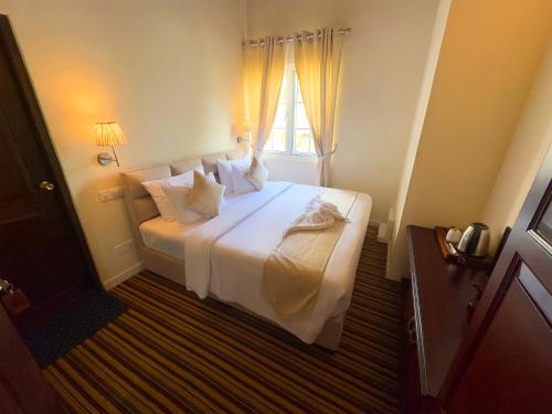 a bedroom with a large white bed with a window at The Tapherini Bungalow in Nuwara Eliya
