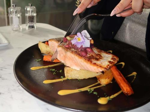 a person holding a fork and a plate of food at Mercure Bordeaux Aéroport in Mérignac