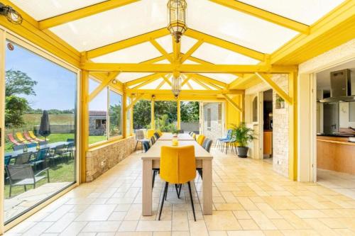 a large conservatory with a table and yellow chairs at Gîte Refuge des Amis in La Gaubretière