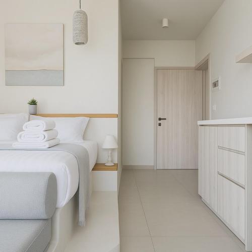 a white bedroom with a bed and a cabinet at Gloria Luxury Suites in Kallithea Halkidikis