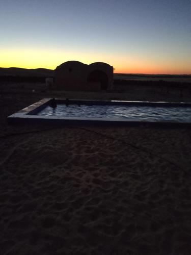 a swimming pool in the middle of the desert at sunset at sabrina camp in Siwa