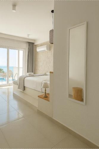 a white bedroom with a bed and a large window at Gloria Luxury Suites in Kallithea Halkidikis