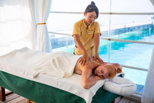 a woman is giving a man a massage on a bed at Diamonds Athuruga Maldives Resort & Spa in Athuruga Island