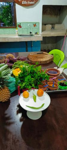 a table with a plate of fruit and vegetables on it at Adisham village home in Haputale
