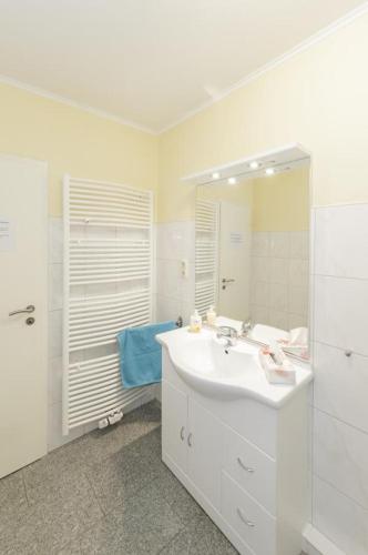 a white bathroom with a sink and a shower at Marbijes Appartementhaus in Cuxhaven