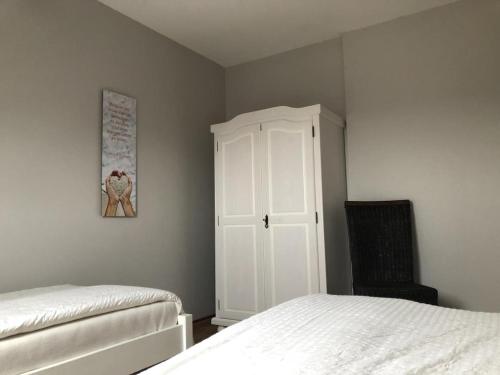 a bedroom with a bed and a white cabinet at Marbijes Appartementhaus in Cuxhaven