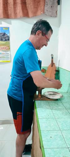 a man standing at a counter making a pizza at Adisham village home in Haputale