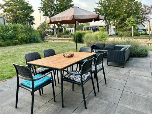 a wooden table and chairs with an umbrella at Marina Strandbad Chalet Sand & Seele Haus Nr 355 in Olburgen