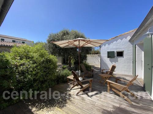 a wooden deck with benches and an umbrella at La Villa de Hurlevent in Les Portes