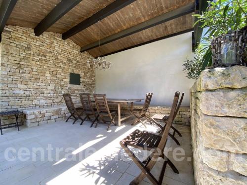 a patio with a table and chairs and a stone wall at La Villa de Hurlevent in Les Portes