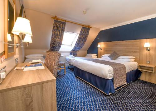 a hotel room with two beds and a desk at The Queens Hotel & Victoria Cloisters Apartments in York