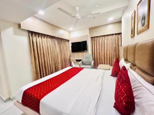 une chambre avec un grand lit avec des oreillers rouges dans l'établissement Hotel Shaligram Inn, à Ahmedabad