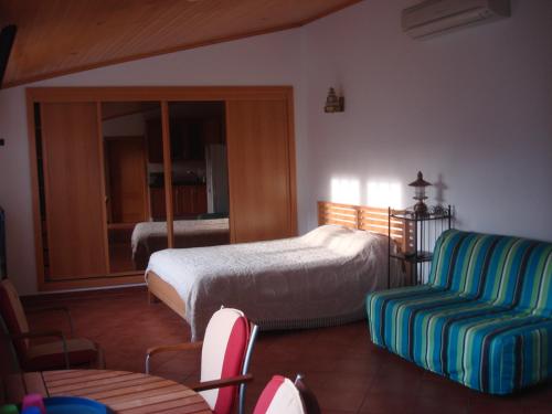 a bedroom with a bed and a couch and a chair at Guest House dos Olivais in Azeitao
